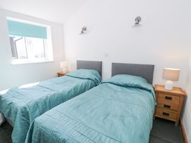 A bedroom with two single beds with blue bedding and wooden nightstands with lamps at Bwthyn y Coediwr (The Woodcutters Cottage) in Tan Y Bwlch Maentwrog