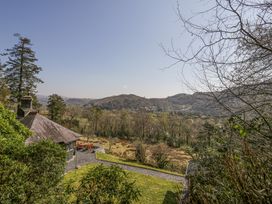 A house with outdoor seating and a gravel path overlooking trees and hills at Bwthyn y Coediwr The Woodcutters Cottage in Tan Y Bwlch Maentwrog