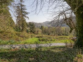 A garden with a gravel path and trees overlooking hills and distant houses at Bwthyn y Coediwr The Woodcutters Cottage in Tan Y Bwlch Maentwrog
