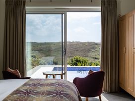 A bedroom with a view of the pool and hills at Trevean in Mullion