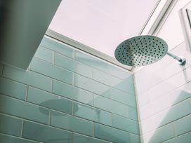 A shower head with tiled walls and a skylight at Trevean in Mullion