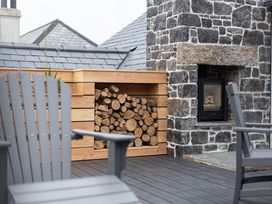 An outdoor area with stacked logs and a stone fireplace at Trevean in Mullion