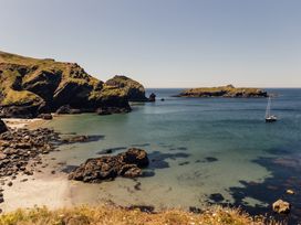 A coastal scene with a boat in the water and rocky shore at Trevean in Mullion