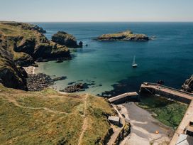 A coastline with a pier and sailboat at Trevean in Mullion