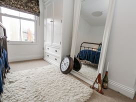 A bedroom with a mirror and a clock at Fisherman’s Cottage