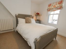 A bedroom with a bed and a vase on a table at Fisherman’s Cottage
