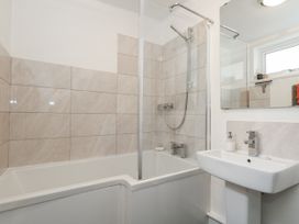 A bathroom featuring a bathtub with shower and a sink at Fisherman’s Cottage