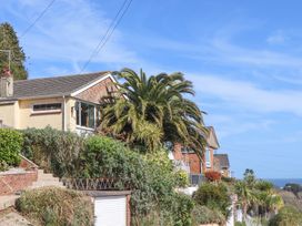 A residential street with houses palm trees and ocean view at House of Emma in Paignton