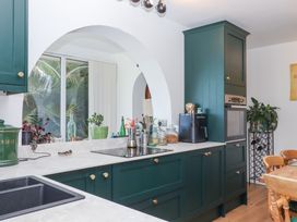 A kitchen with green cabinets white countertops a black sink a built-in oven and plants on a counter at House of Emma in Paignton