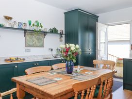 A kitchen with a wooden dining table and chairs green cabinets and an open door at House of Emma Paignton