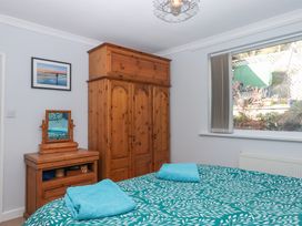 A bedroom with wooden wardrobe and dresser with mirror and bed with teal patterned duvet at House of Emma in Paignton