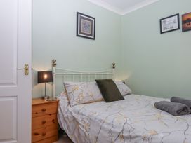 A bedroom with a bed with floral bedspread a pillow a wooden nightstand with a lamp and framed pictures on the wall at House of Emma in Paignton