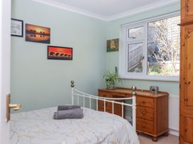 A bedroom with a metal bed frame two folded towels on the bed wooden dresser a plant on the dresser and three framed pictures on the wall at House of Emma in Paignton