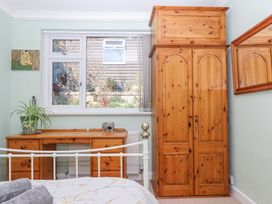 A bedroom with a wooden wardrobe desk and window with a view of a garden at House of Emma in Paignton