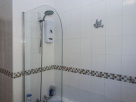 A bathroom shower area with a glass screen and a wall-mounted electric shower at House of Emma in Paignton
