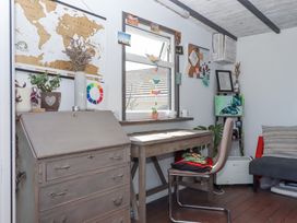 A workspace with a wooden desk and chair near a window with plants books and artwork at House of Emma in Paignton