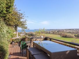 A balcony with outdoor furniture and a view of a coastal town and open fields at House of Emma in Paignton