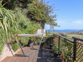 A balcony with a hammock stand and potted plants overlooking the sea at House of Emma in Paignton