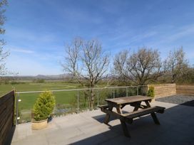 An outdoor area with a wooden table and benches overlooking fields at Tirionfa in Talsarnau