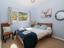 A bedroom with a bed, chair, and window at Tirionfa in Talsarnau