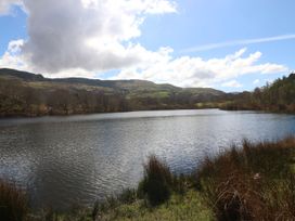 A lake surrounded by mountains and trees at Tirionfa in Talsarnau