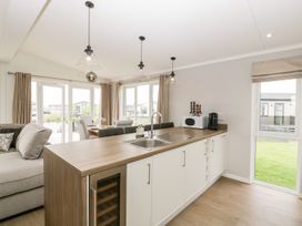A kitchen with an island, sink, microwave, coffee machine, and dining area with chairs at Summerdown in Brean