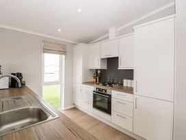 A kitchen with white cabinets a stove an oven a sink a window and wooden countertops at Summerdown in Brean