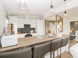 A kitchen with a wooden countertop island and four bar stools at Summerdown in Brean