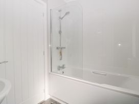 A bathroom with a bathtub and shower and a white door at Summerdown in Brean
