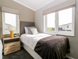 A bedroom with a single bed a bedside table with a lamp and a window at Summerdown Brean