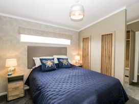 A bedroom with a bed with dark blue bedding and bee pillows at Summerdown in Brean