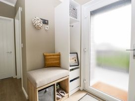 A hallway with a cushioned bench and storage cubbies next to a frosted glass door at Summerdown in Brean