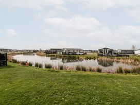 Small houses near a pond with grassy area in the foreground at Summerdown in Brean