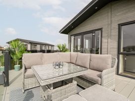 An outdoor deck with wicker furniture and cushions outside a modern house at Summerdown in Brean