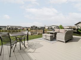 A patio with seating and tables overlooking a pond with houses in the background at Summerdown Brean