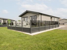 A modern single-story building with a fenced outdoor seating area on grass at Summerdown in Brean