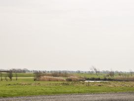 A grassy field with a small water body and sparse trees under an overcast sky at Summerdown in Brean