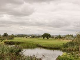 A golf course with a pond and ducks under a cloudy sky at Summerdown in Brean