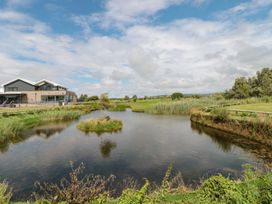 A pond with greenery and a building nearby at Summerdown in Brean