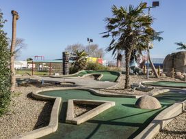 An outdoor mini golf course with palm trees and tiki statues at Summerdown in Brean