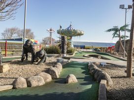 An outdoor mini golf course with animal statues and an amusement ride in the background at Summerdown in Brean