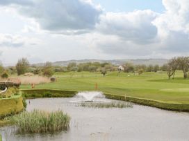 A golf course with a pond and fountain surrounded by grass and trees at Summerdown in Brean