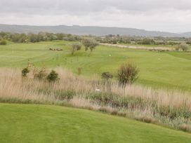 A golf course with green grass water hazard and hills in the background at Summerdown in Brean