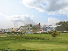 A golf course putting green with amusement park rides and a ferris wheel in the background at Summerdown in Brean