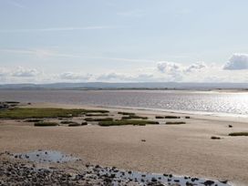 A coastal landscape with sandy shore patches of grass water and hills in the distance at Summerdown in Brean