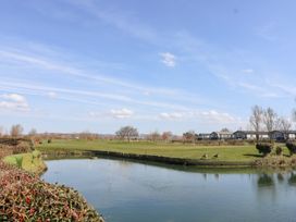 A golf course with a water hazard and two birds on the grass near houses at Summerdown in Brean