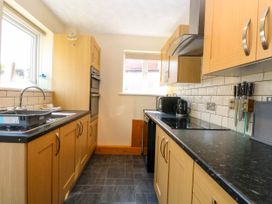 A kitchen with wooden cabinets black countertops a sink oven stove microwave and knives at Sweetacres in Hemsby