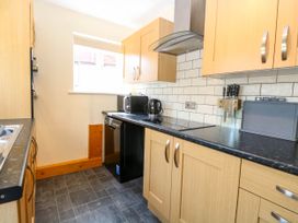 A kitchen with wooden cabinets black countertops a window and black appliances at Sweetacres in Hemsby