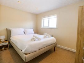 A bedroom with a double bed two rolled towels bedside table lamp and window at Sweetacres in Hemsby