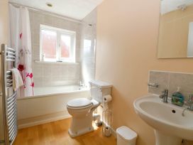 A bathroom with a bathtub a toilet a sink towel rack and a window at Sweetacres in Hemsby